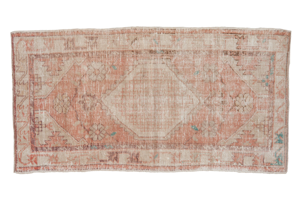 A vintage distressed Oushak rug runner with a hexagonal medallion in faded pink, ivory, and sand hues.
