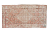 A vintage distressed Oushak rug runner with a hexagonal medallion in faded pink, ivory, and sand hues.