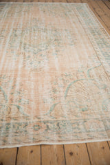 Distressed texture of a vintage Oushak rug, showing blush and faded teal design.