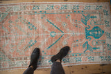 Distressed vintage Oushak rug runner with soft melon, teal, and brown tones, shown to scale.