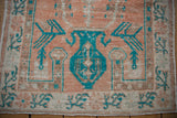 Ornate turquoise vase prayer motif on a distressed vintage Oushak rug with a pale cantaloupe field.