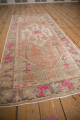 Distressed vintage Oushak rug detail with fuchsia florals, dusty blush, beige, and worn pile.