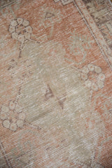 Textured, distressed vintage Oushak pile with muted blush and pale green floral motifs.