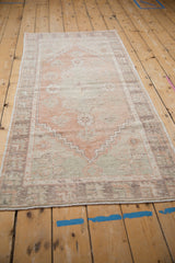 Distressed Oushak runner pile showing dusty blush, sea foam green, and stepped pattern.