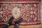 Distressed Turkish Oushak rug runner, cherry red and sand field with visible wear and floral motifs.