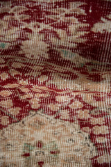 Distressed vintage Oushak rug showing worn pile texture in cherry red, sand.