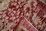 Distressed vintage Oushak rug showing worn cherry red and beige floral pattern, red selvage.