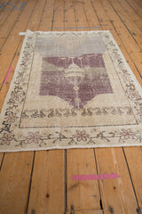 Distressed vintage Sparta rug corner with mauve floral border, visible foundation wear, and fringe.