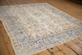 Distressed Sparta rug edge, showing worn pile, visible foundation, and blue arabesque border.