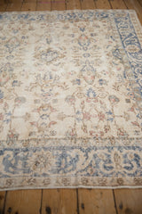 Distressed Turkish Sparta rug with faded ivory, blue floral vinery, and visible foundation.