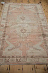 Distressed vintage Oushak rug pile texture with faded apricot, teal, and ivory geometric motifs.