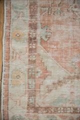 Distressed Oushak rug texture detail with faded apricot, teal, and ivory geometric design.