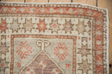 Distressed Oushak rug corner, showing geometric starbursts and stylized pinwheel florals.