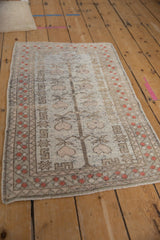 Pale raspberry fruit and tree of life motif on distressed Oushak rug pile.