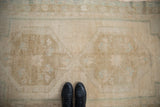 Faded motifs and abrashed texture of distressed Oushak runner, with black boots.