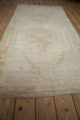 Vintage Oushak runner's short pile, original side selvage, and faded seafoam green border.