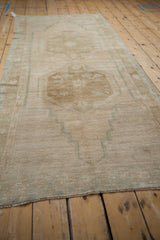 Abrashed antique ivory pile of a distressed Oushak rug with faded seafoam geometric details.