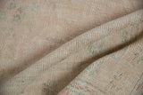 Close-up of vintage distressed Oushak rug pile, showing wear to knot heads with pale pink and blue flecks.