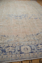 Distressed vintage Oushak carpet with worn cream pile, visible foundation, and faded blue motifs.