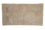 Distressed vintage Oushak rug with soft, faded cream, beige, and dusty green geometric patterns.