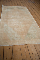 Distressed Oushak rug with cream, beige, seafoam green tones, and visible foundation.