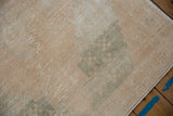Distressed cream and beige pile, showing faded seafoam green geometric motifs and wear.