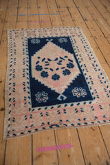 Distressed vintage Oushak rug corner; pink border, cobalt blue stepped floral design.