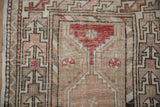 Distressed Oushak pile showing geometric patterns and subtle pinwheel florals in beige, rose, and charcoal.