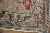 Close-up of a distressed Oushak rug's primitive geometric border in beige and muted cherry red.