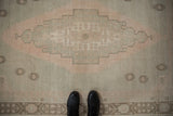 Distressed Oushak rug showcasing a soft seafoam green, dusty rose, and ivory stepped medallion.