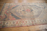 Distressed Oushak rug corner with secured end, selvage, faded red motifs.