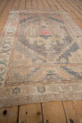 Hand-knotted distressed Oushak rug featuring faded raspberry, blue, and ivory geometric patterns.