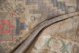 Distressed texture and muted geometric patterns on a vintage Oushak rug with soft folds.