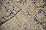 Folded corner of distressed Oushak carpet, cream field, cobalt blue pattern, foundation showing through.