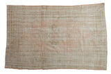 Vintage distressed Oushak rug with a faint medallion design in pale pink, ivory, and seafoam green.