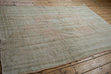 Angled view of a distressed Oushak rug with an abrashed ground and even wear.