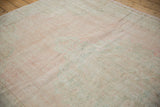 Distressed Oushak rug's worn pile texture, showing faded pale pink, ivory, and seafoam.