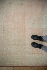 Faded pale pink and ivory vintage Oushak rug with distressed pile revealing foundation.