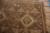Distressed Kars rug's chocolate brown geometric patterns with ivory and bright pink accents.