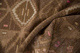 Distressed chocolate brown Kars rug with folded texture, showing pink geometric checkered flowers.