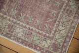 Worn pile showing exposed knot heads and the intact side cord selvage on a vintage rug corner.