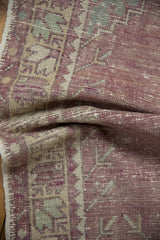 Soft, pliable texture of a distressed vintage Oushak rug in muted purple, ivory, and mint.