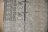 Distressed vintage Oushak rug with faded charcoal tree line and pale rose fruit.