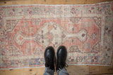A person stands on a vintage distressed Oushak runner, showing scale and worn texture.