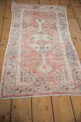 Angled view of a distressed Turkish Oushak runner with a stepped medallion in blush and mauve tones.