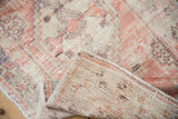 Distressed vintage Oushak rug with a folded corner revealing its hand-knotted foundation.