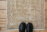 Distressed sand and antique ivory Oushak rug texture, overhead with boots.
