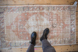 A person's view of the distressed, low-pile texture on a vintage Turkish Oushak rug runner.