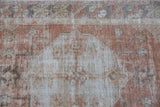 Time-softened serrated medallion with floral details on a distressed vintage Oushak rug.