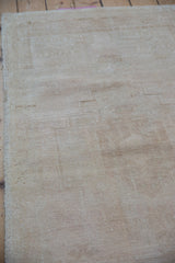 Textured distressed Oushak rug pile with abrash field in muted ivory and beige.